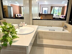 A modern bathroom with a large sink, bathtub, and a potted plant.