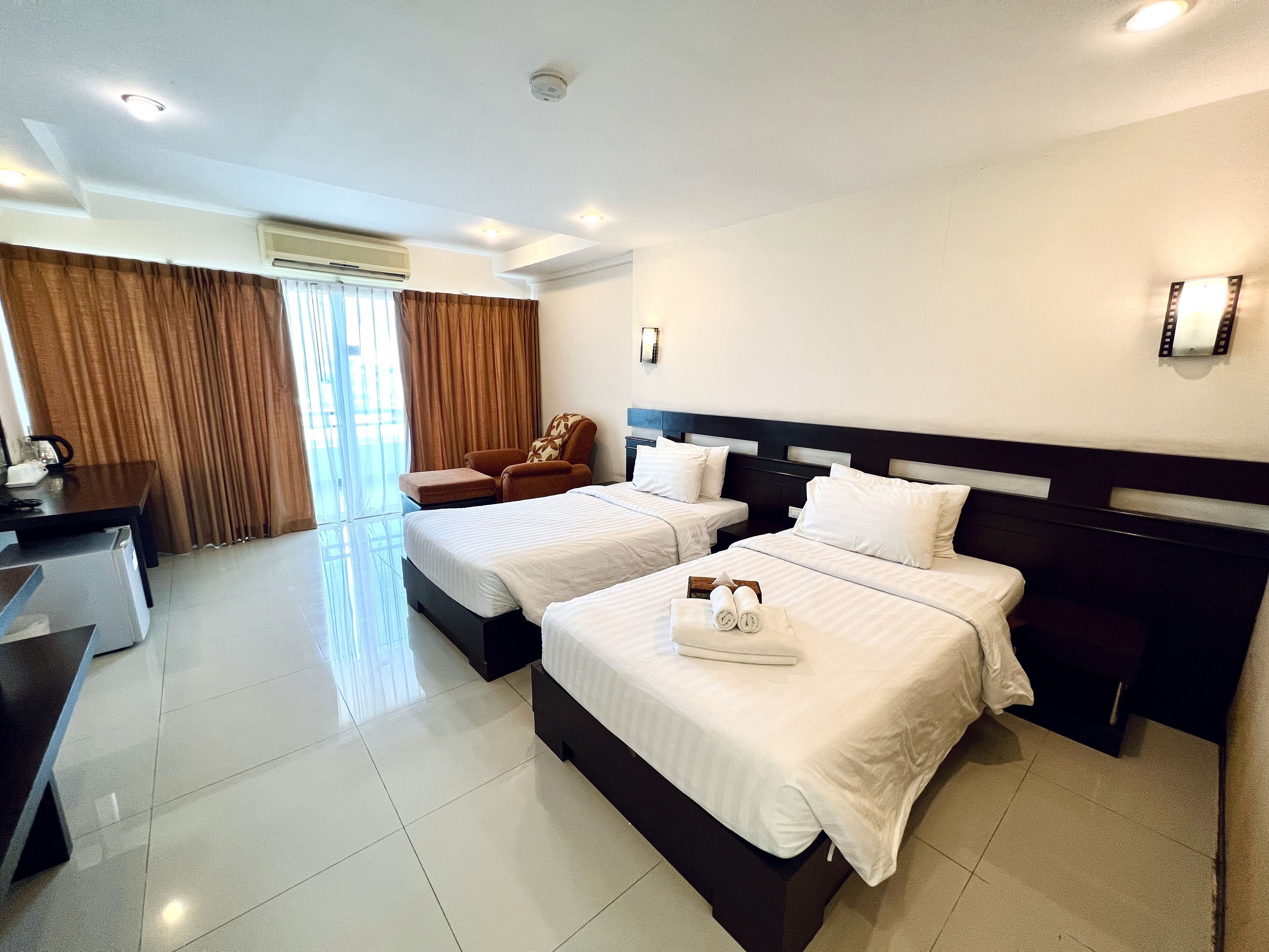 A hotel room with two beds, a desk, and a chair.