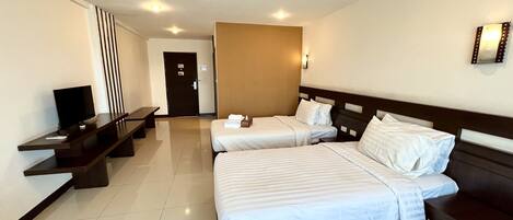 Habitación de hotel con dos camas, televisor, escritorio y puerta al baño.