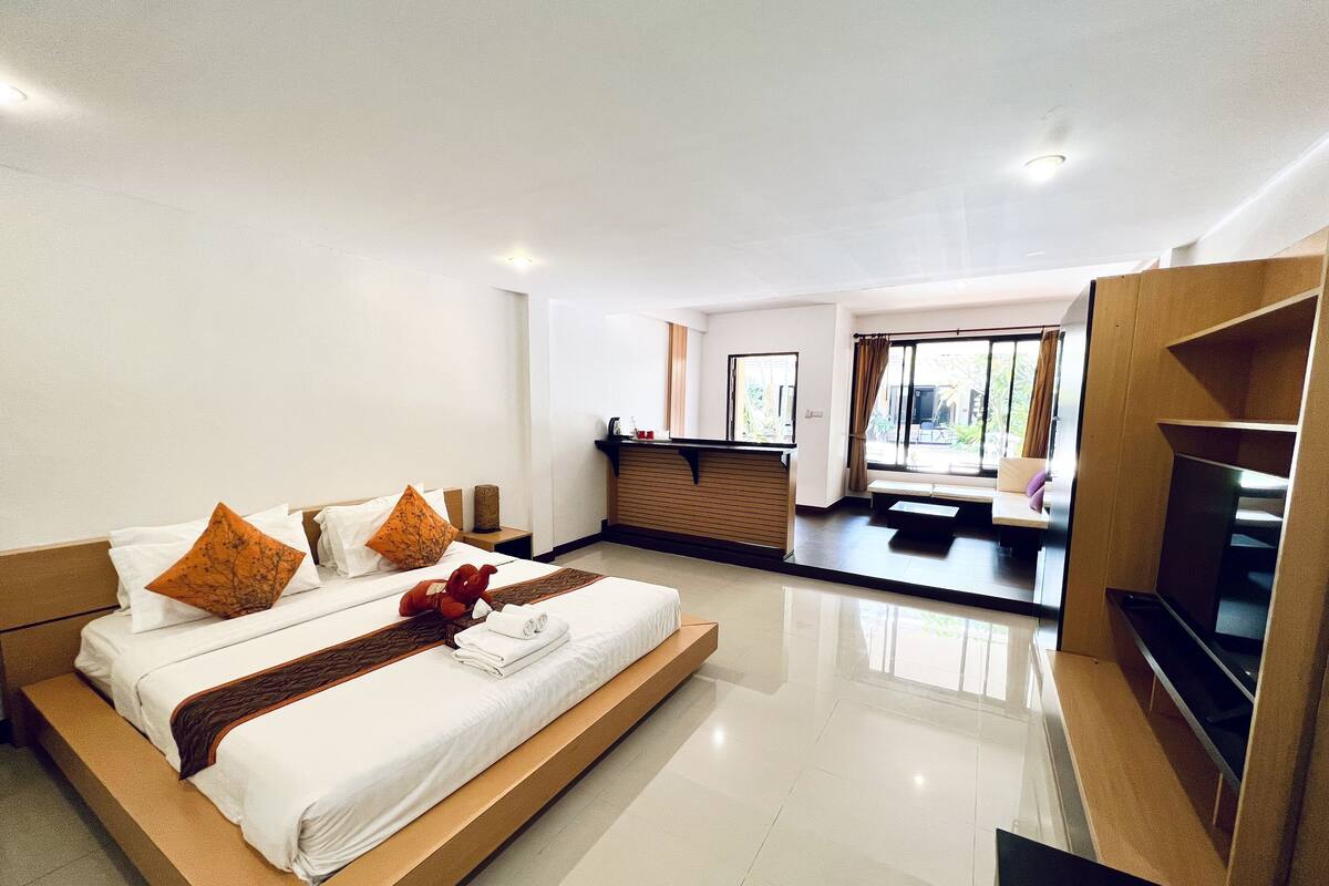 A modern hotel room with a large bed, a seating area, and a TV.