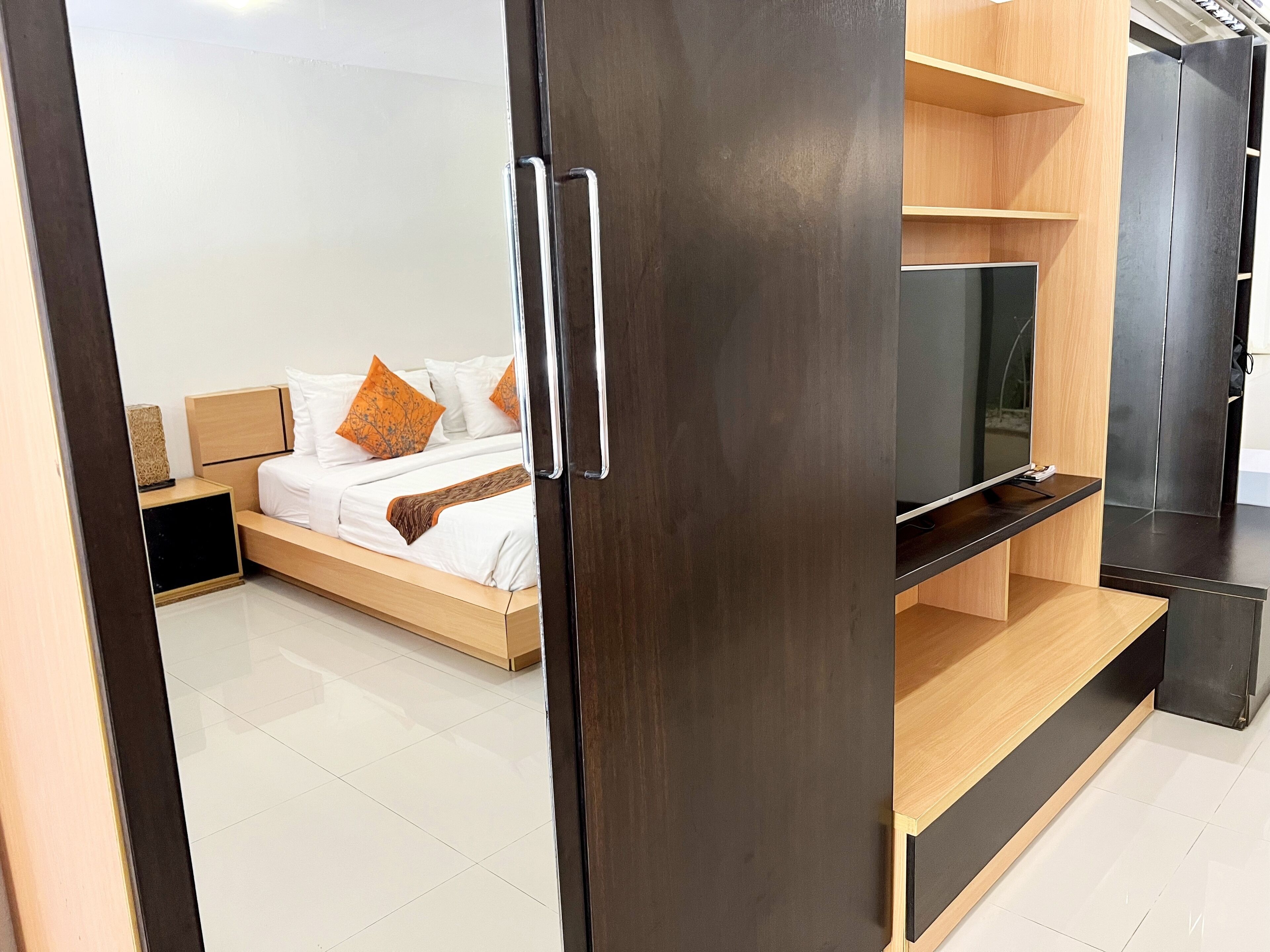 Un dormitorio moderno con cama, televisor y armario.