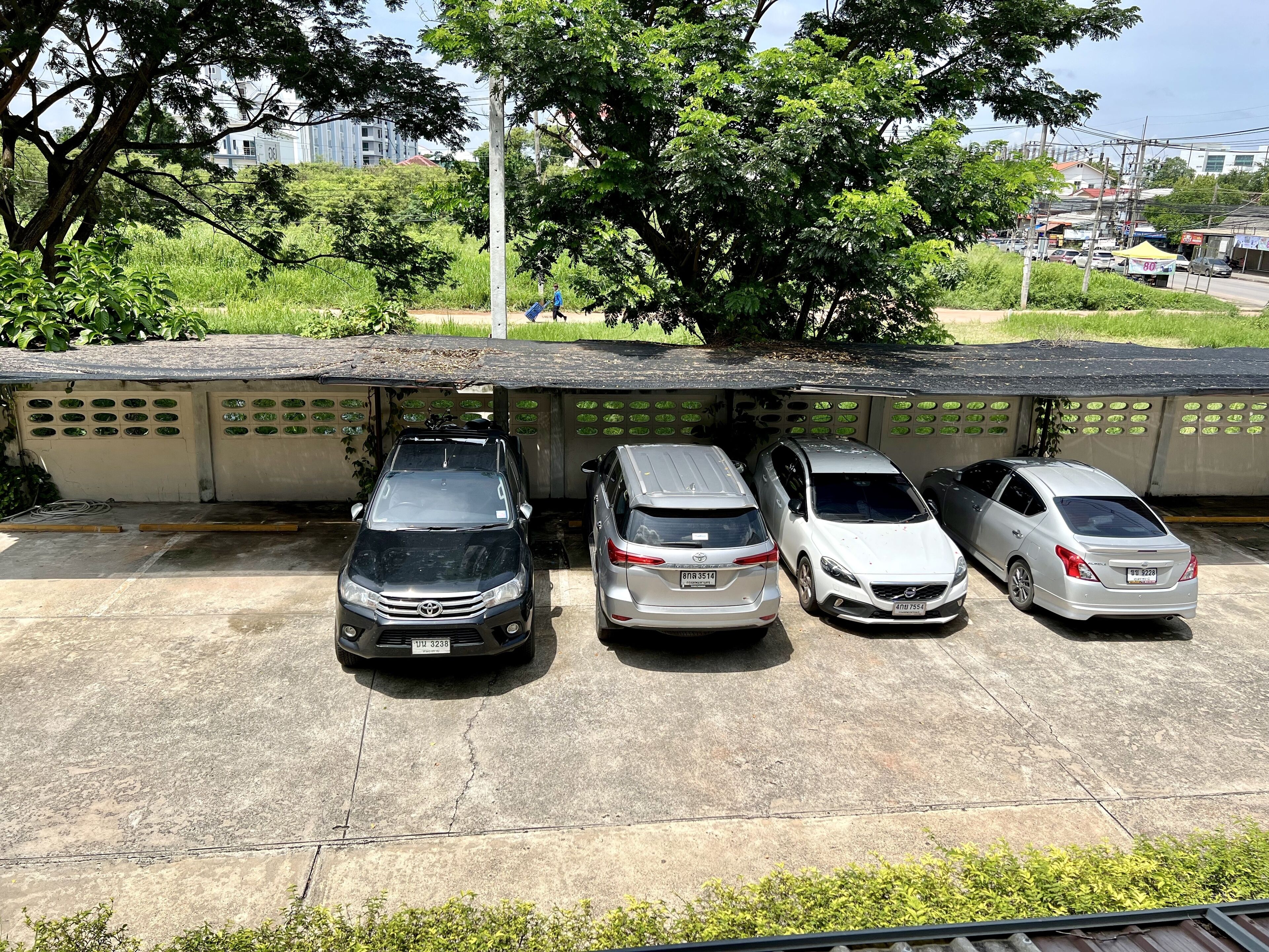 A parking area with four cars parked under a covered structure.