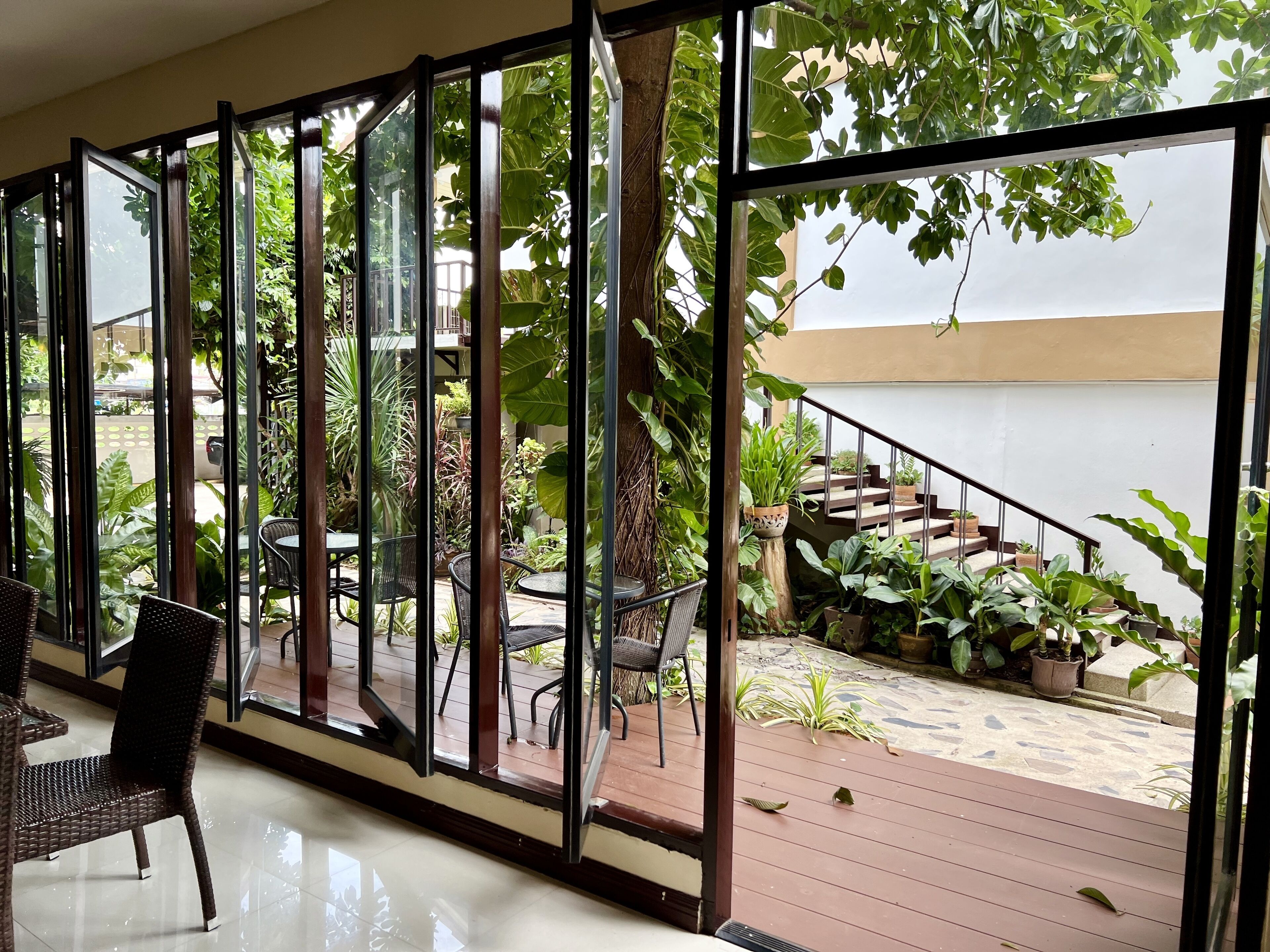 A room with large glass doors leading to an outdoor area with a wooden deck and potted plants.