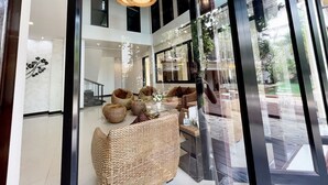 A modern interior with wicker furniture, large windows, and a glass partition.