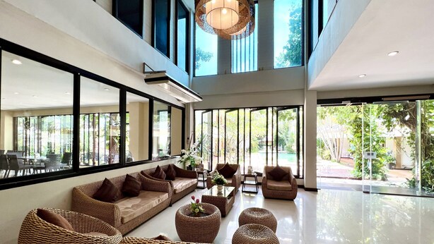 A spacious indoor area with a large sofa set, wicker ottomans, and a dining table.
