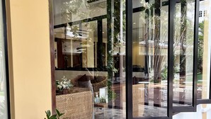 A modern interior with a glass partition, wicker furniture, and a potted plant.
