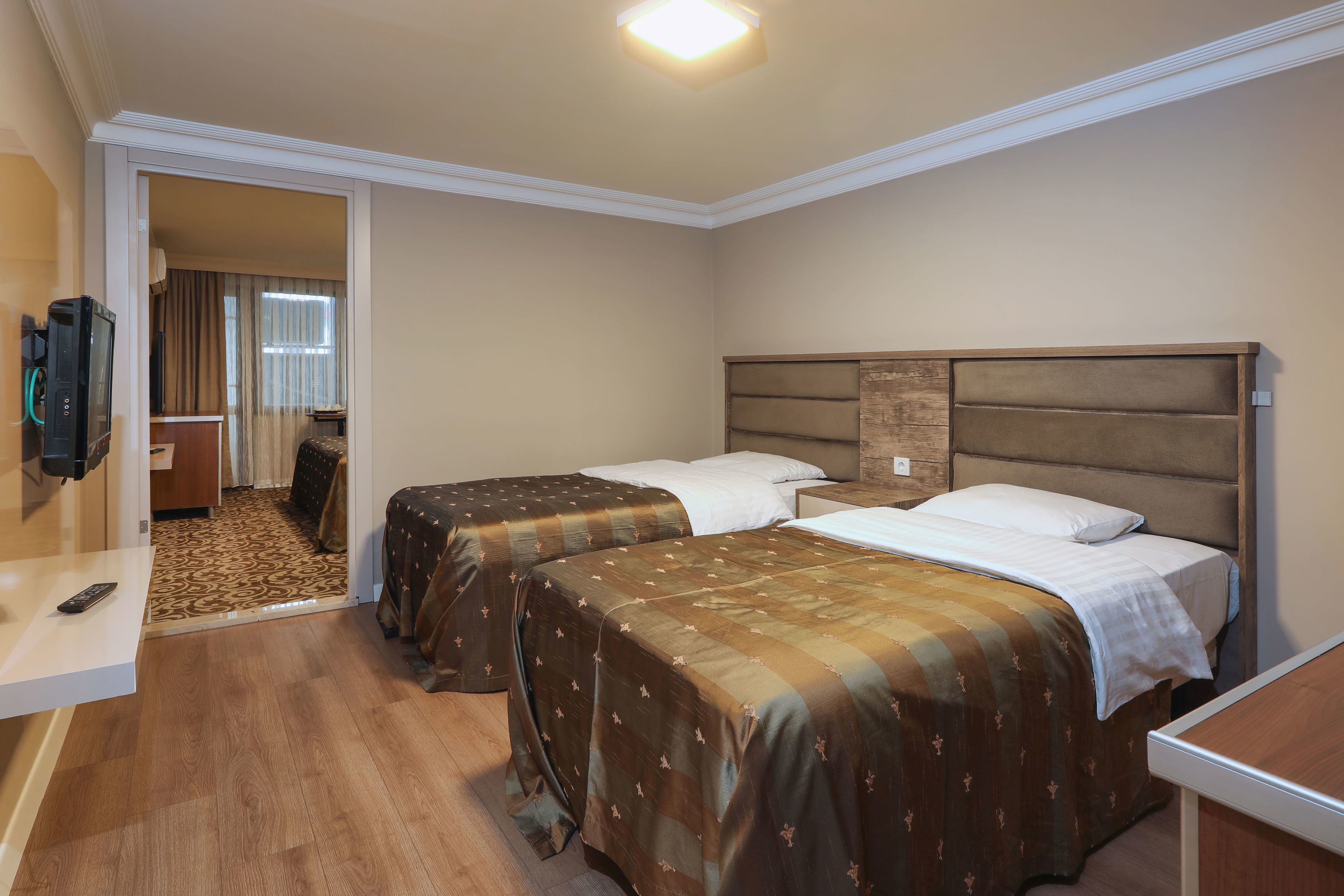 Ein Hotelzimmer mit zwei Betten, einem Fernseher, einem Schreibtisch und einem durch eine geöffnete Tür einsehbaren Badezimmer.
