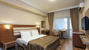 Habitación de hotel con una cama grande, un escritorio, una silla y un televisor.