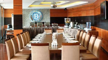A conference room with a long table, chairs, and a logo on the wall.