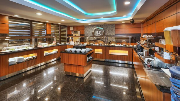Una cocina de hotel moderna con una barra de buffet, que incluye una isla central y varias estaciones de comida.