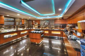 A modern hotel kitchen with a buffet setup, including a central island and multiple food stations. - Balturk Otel Sakarya (Adapazari)