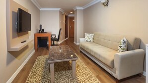 Una sala de estar con una televisión de pantalla plana, un sofá, una mesa de centro y un tapete estampado.