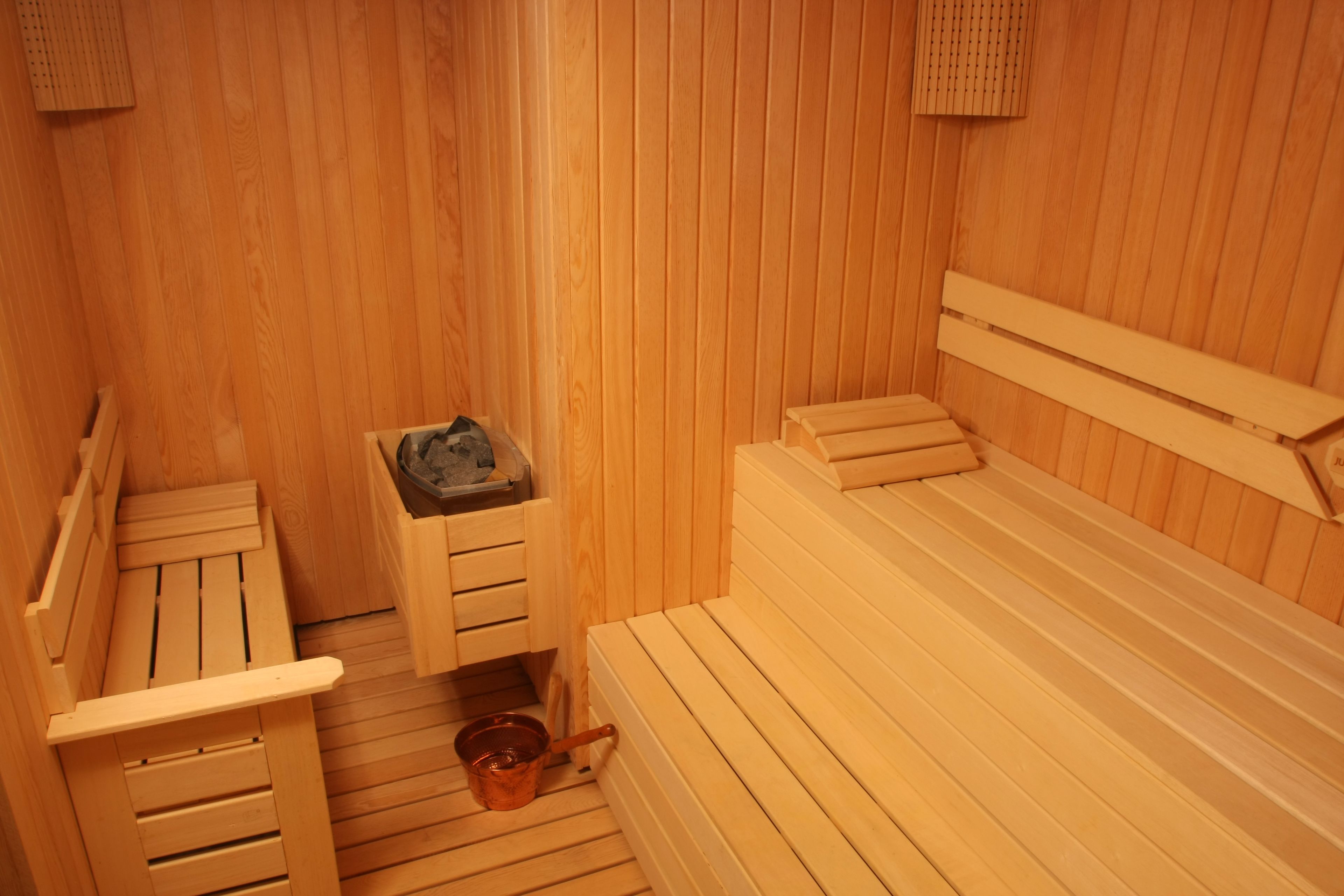 A sauna room with wooden benches and a small wooden table with a bucket.
