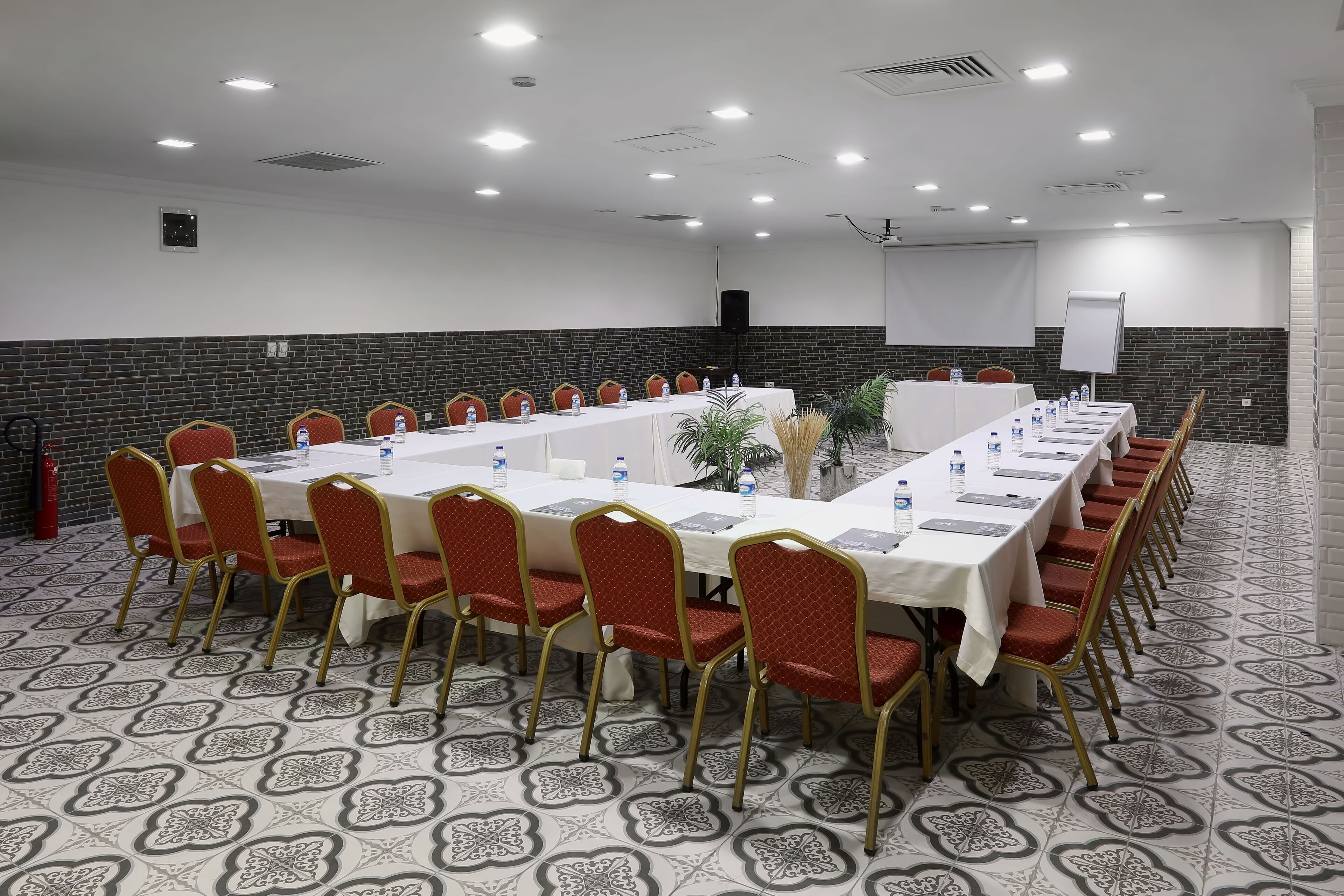 A conference room with a long table, red chairs, and a whiteboard.