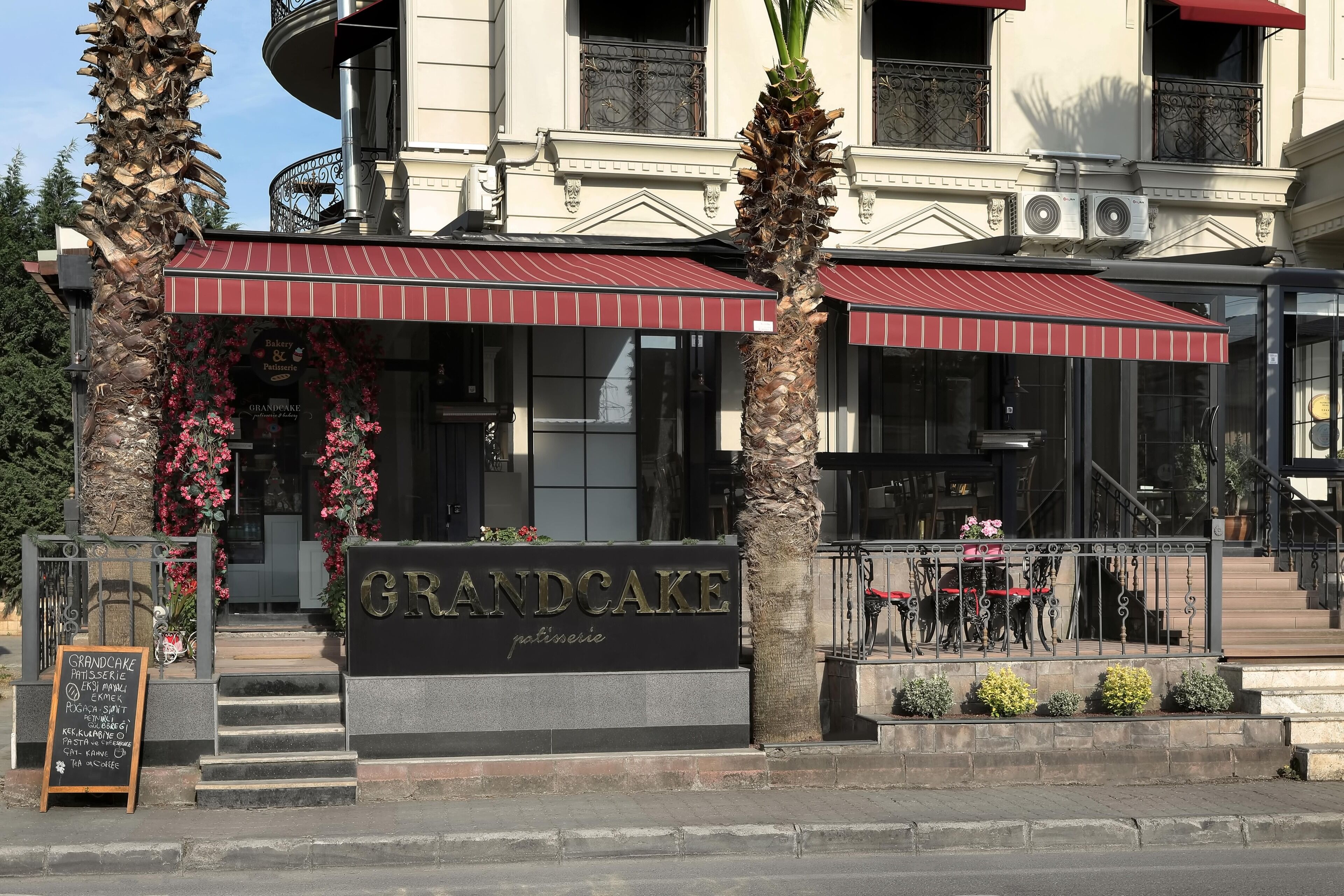 Un edificio con un letrero que dice "GRANDCAKE pastelería" y una escalera que lleva a la entrada.