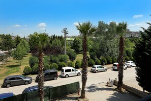 Un estacionamiento con varios coches, rodeado de vegetación y palmeras.