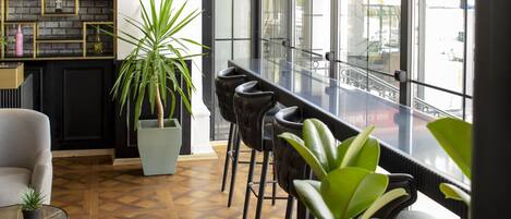Un bar moderno con suelo de parquet de madera, decoración en negro y dorado, y ventanas amplias con vistas a la ciudad.