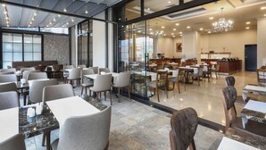 A spacious dining area with multiple tables and chairs, large windows, and a modern chandelier. - New Balturk Hotel Izmit (Izmit)