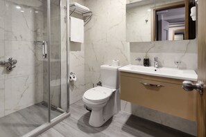 A modern bathroom with a glass shower enclosure, a toilet, and a sink with a marble countertop. - New Balturk Hotel Izmit (Izmit)
