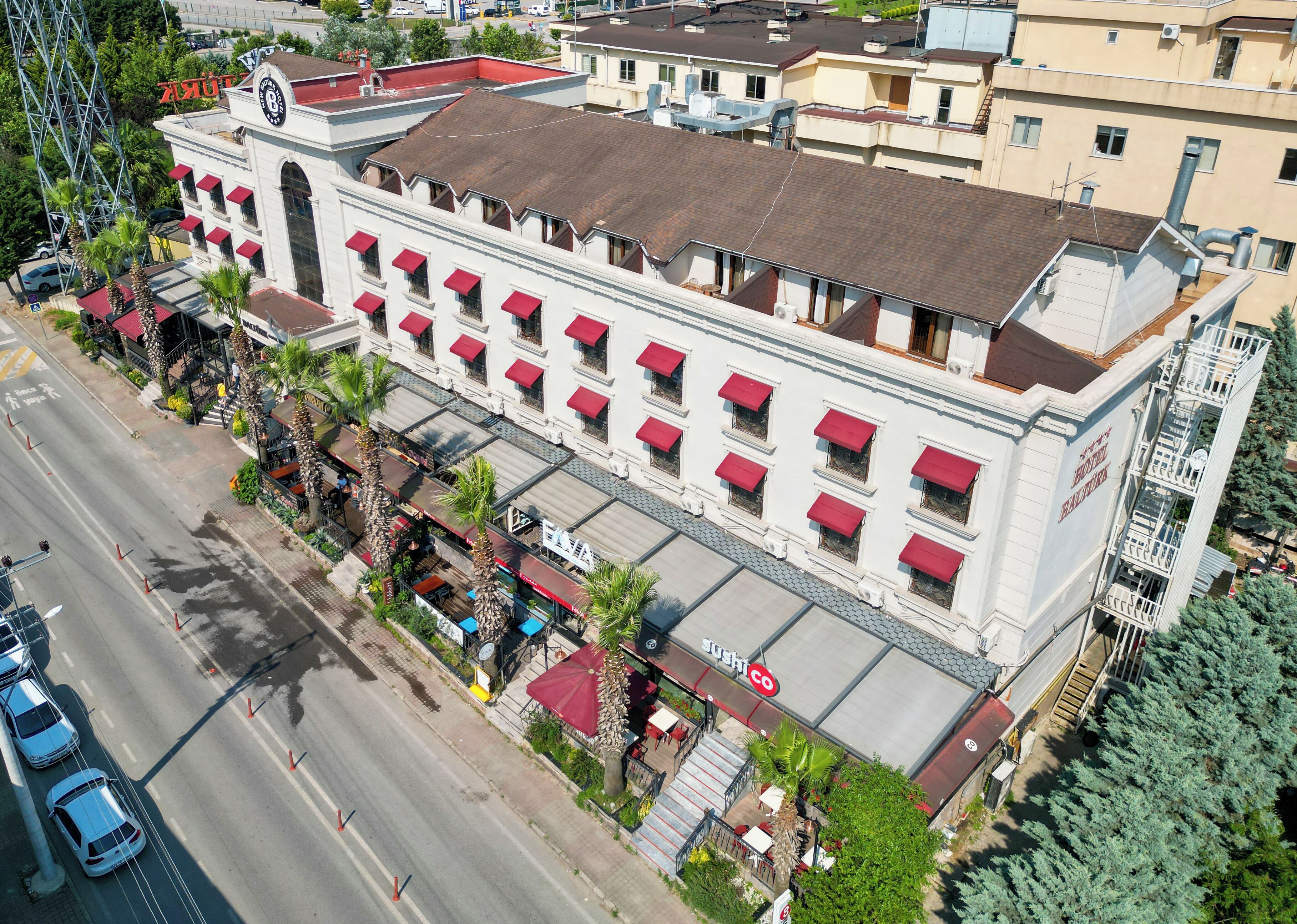 A multi-story hotel with a red awning, a clock tower, and a ground-level restaurant.