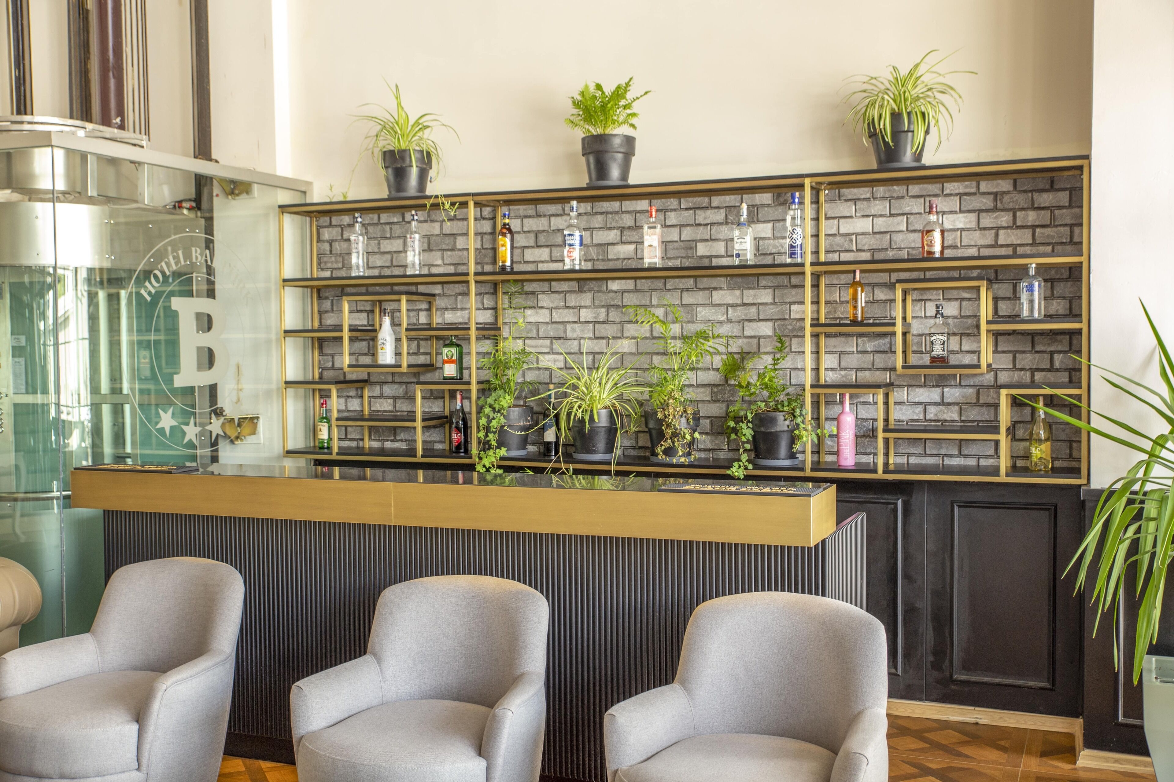 A reception area with a brick wall, shelves with bottles, and potted plants.