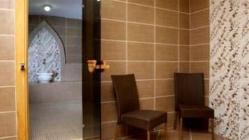 Experience a serene bathroom retreat with a large mirror, comfortable seating, and a stylish tiled wall.