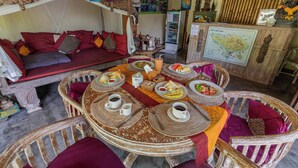 A dining area with a round table set for breakfast, surrounded by wicker chairs. - Alam Pracetha Bali (Ubud)