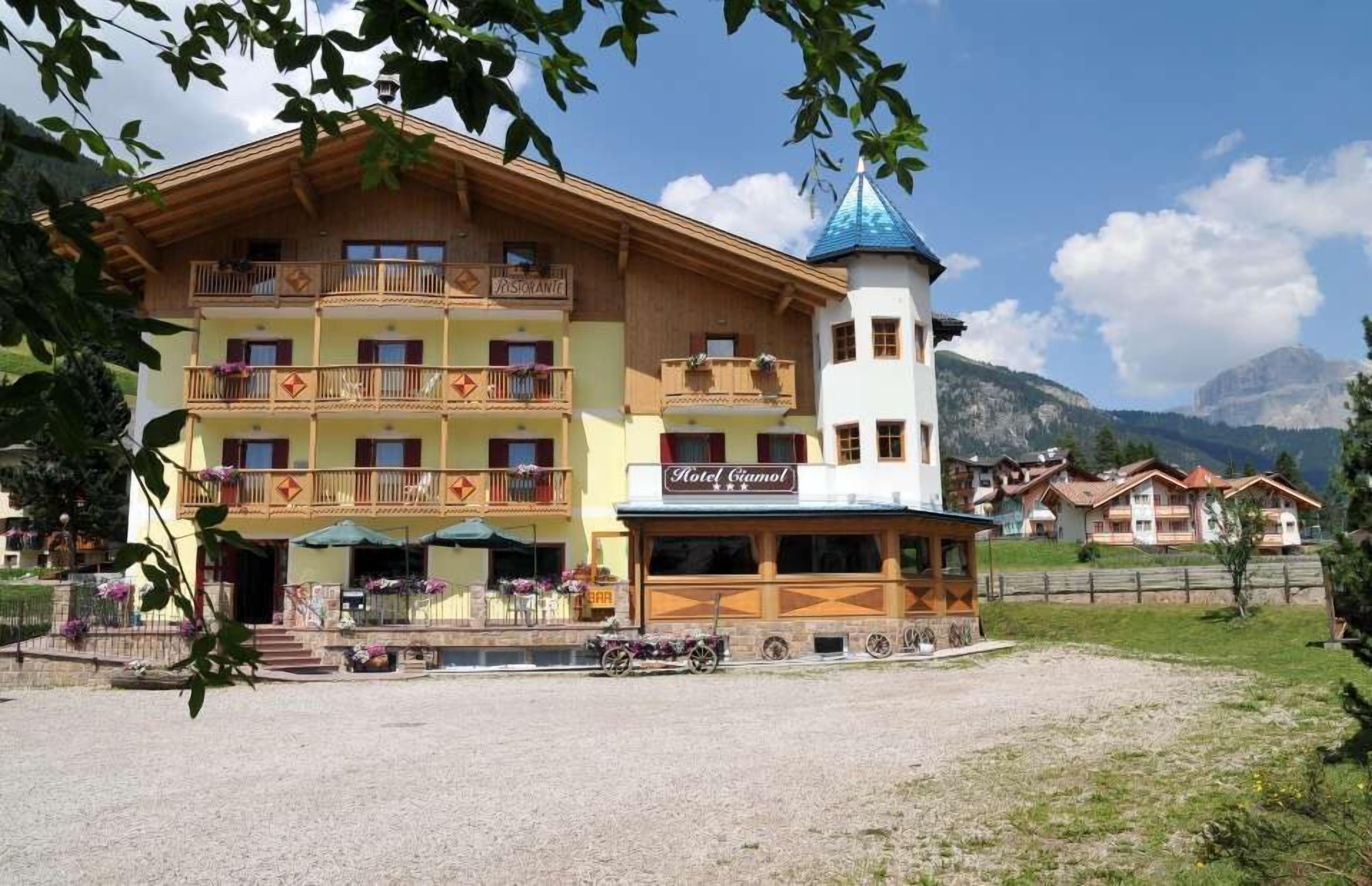 Un immeuble à plusieurs étages, avec une enseigne de restaurant, des balcons et une tour surmontée d’un toit bleu.