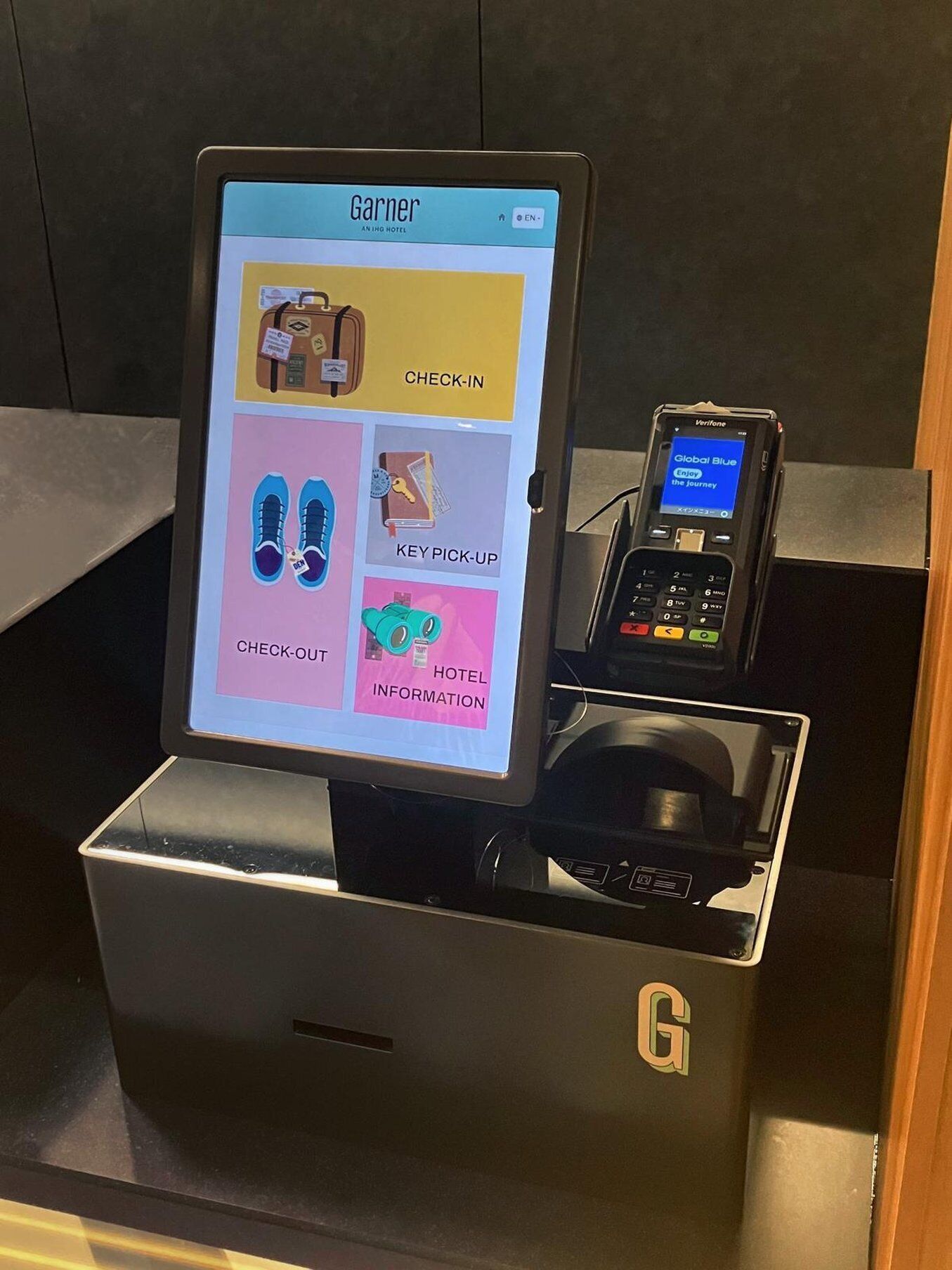 A digital kiosk with a screen displaying options for check-in, key pickup, check-out, and hotel information.