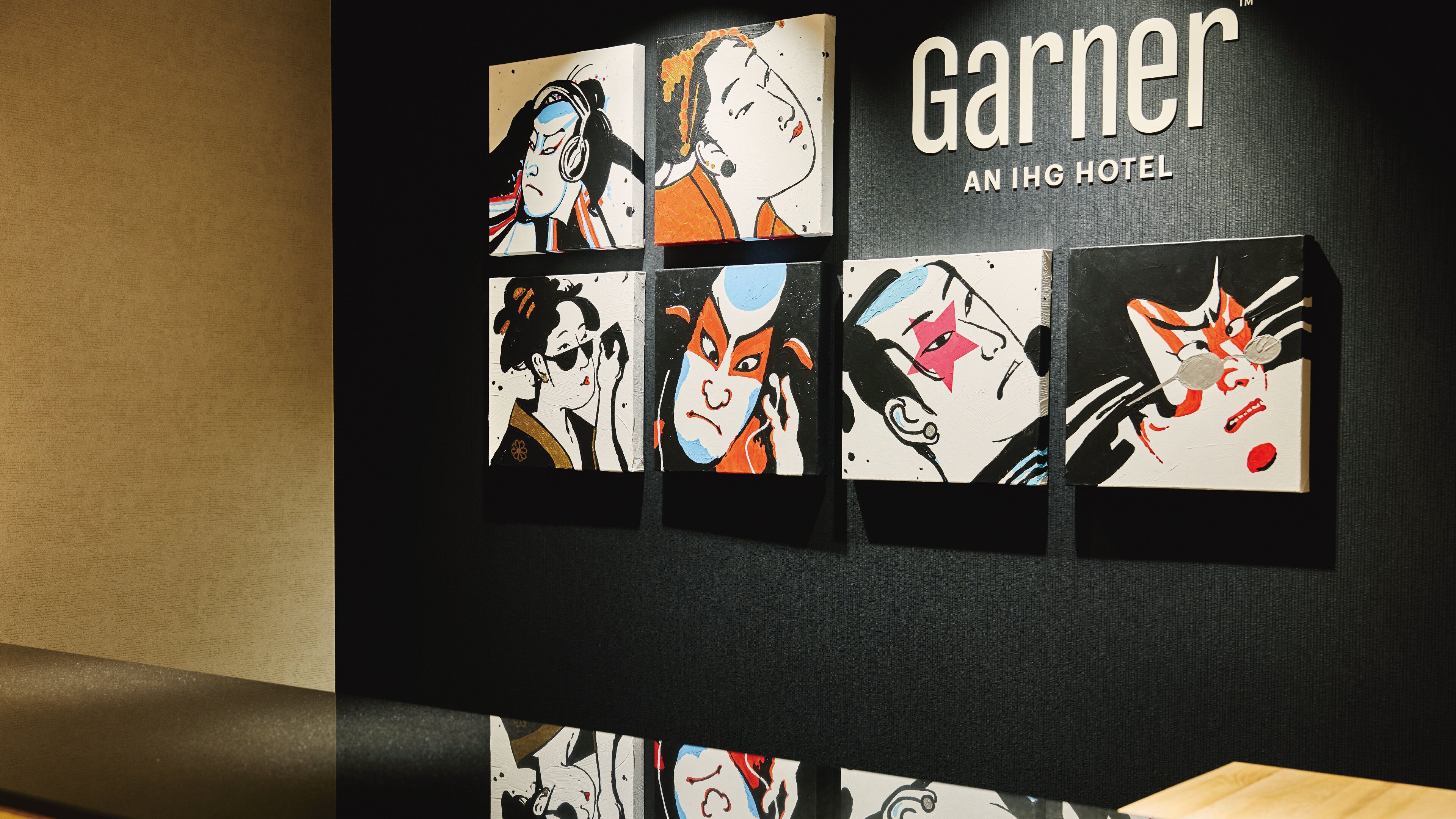 A wall with framed artwork depicting various characters, and the text "Garnier An IHG Hotel".