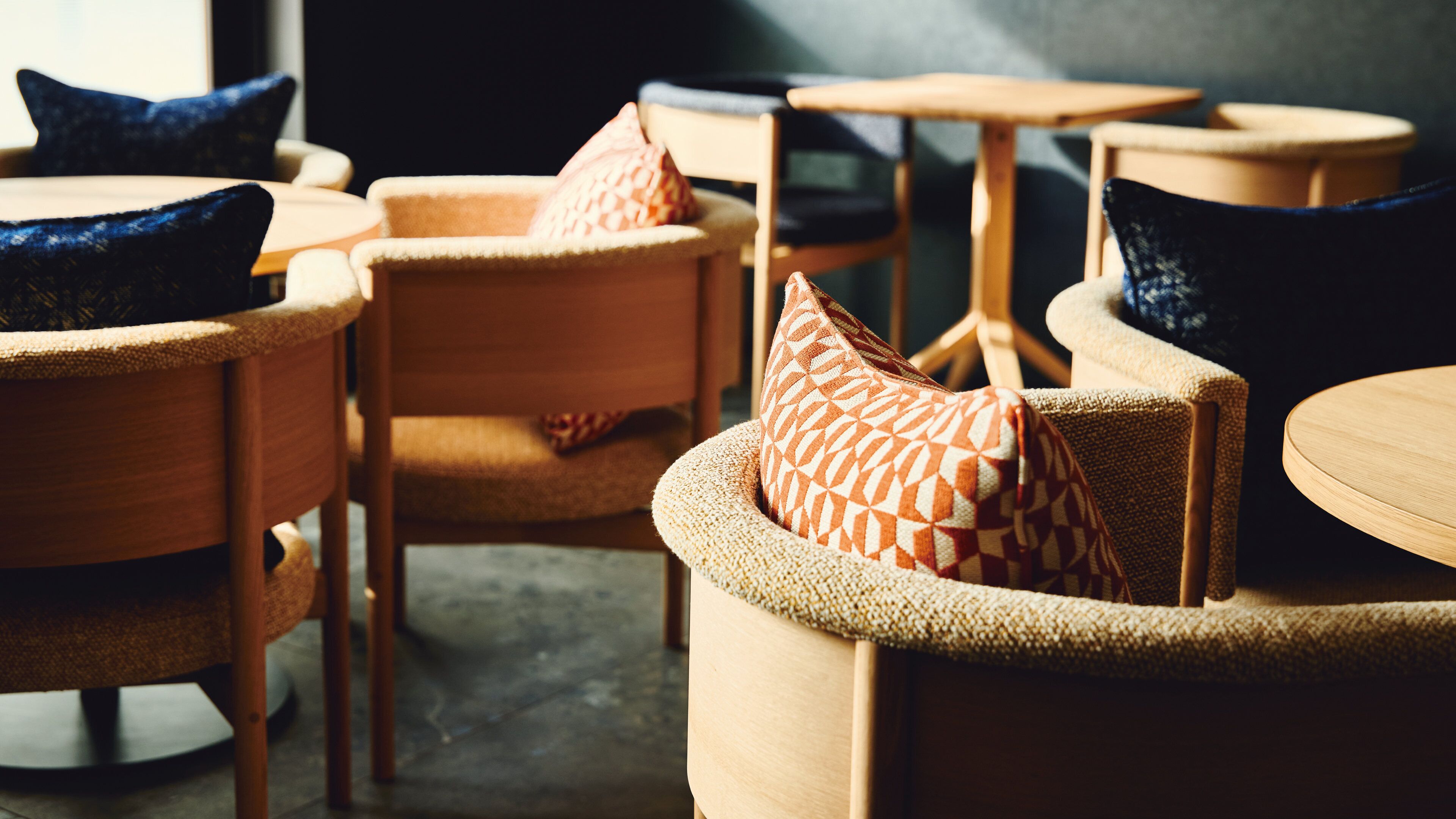 Un coin salon accueillant avec des tables rondes en bois et des fauteuils confortables, agrémenté de coussins aux motifs géométriques.