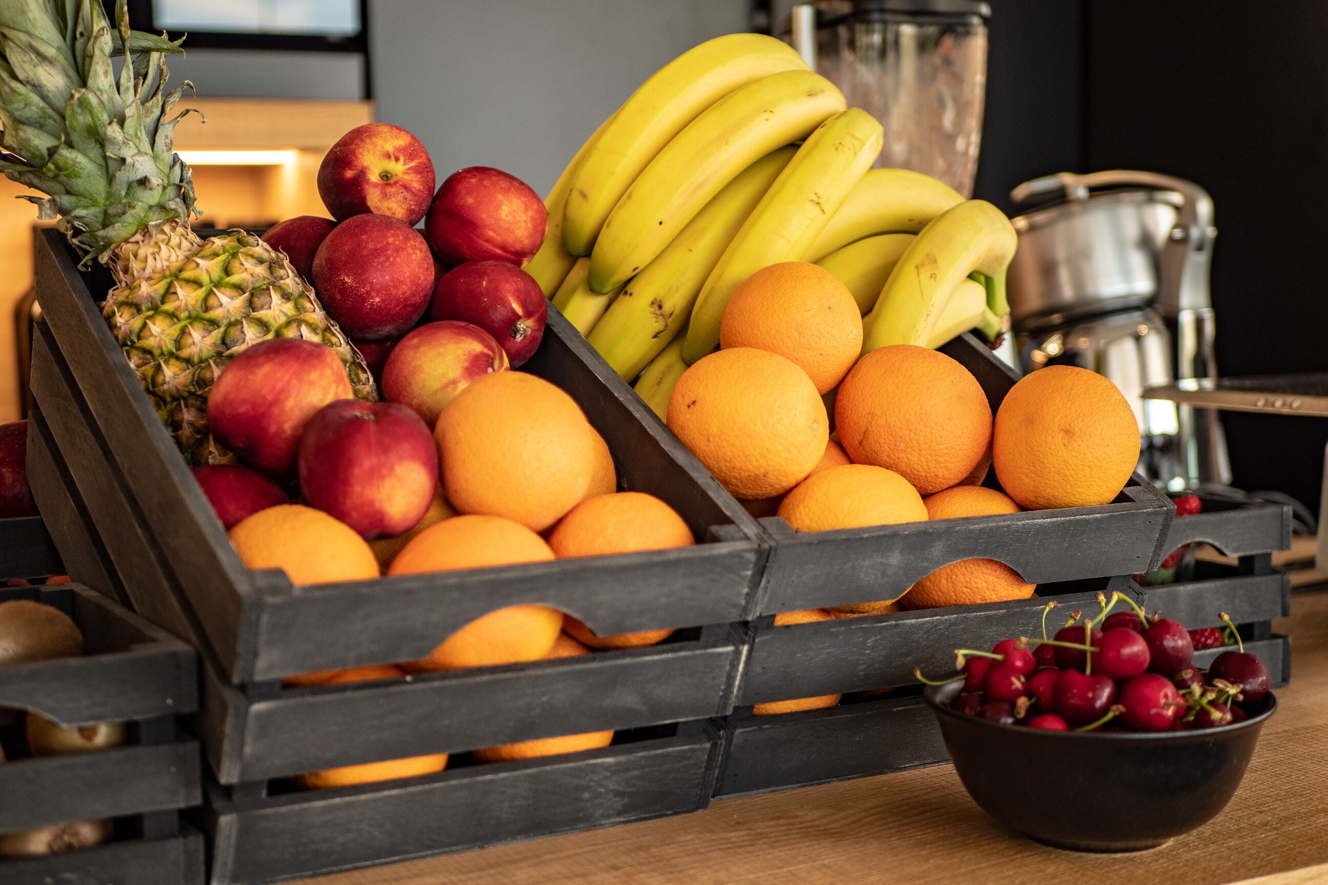 A wooden crate filled with various fruits including apples, bananas, oranges, and a pineapple.
