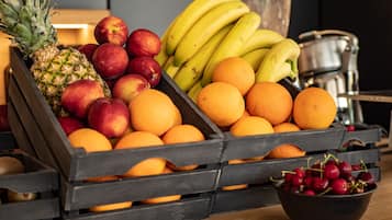 A wooden crate filled with various fruits including apples, bananas, oranges, and a pineapple.