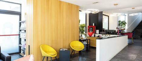 A modern reception area with a wooden accent wall, a reception desk, and two yellow chairs.