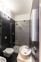Un baño moderno con inodoro, lavabo y ducha.
