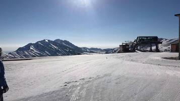 Un paysage de montagne enneigé, avec un ciel dégagé et un télésiège en arrière-plan.