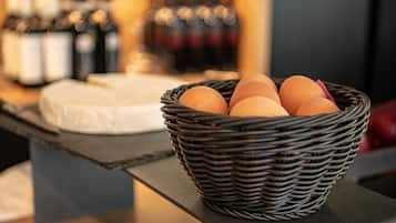 A wicker basket with eggs on a counter, with bottles and a cake in the background.