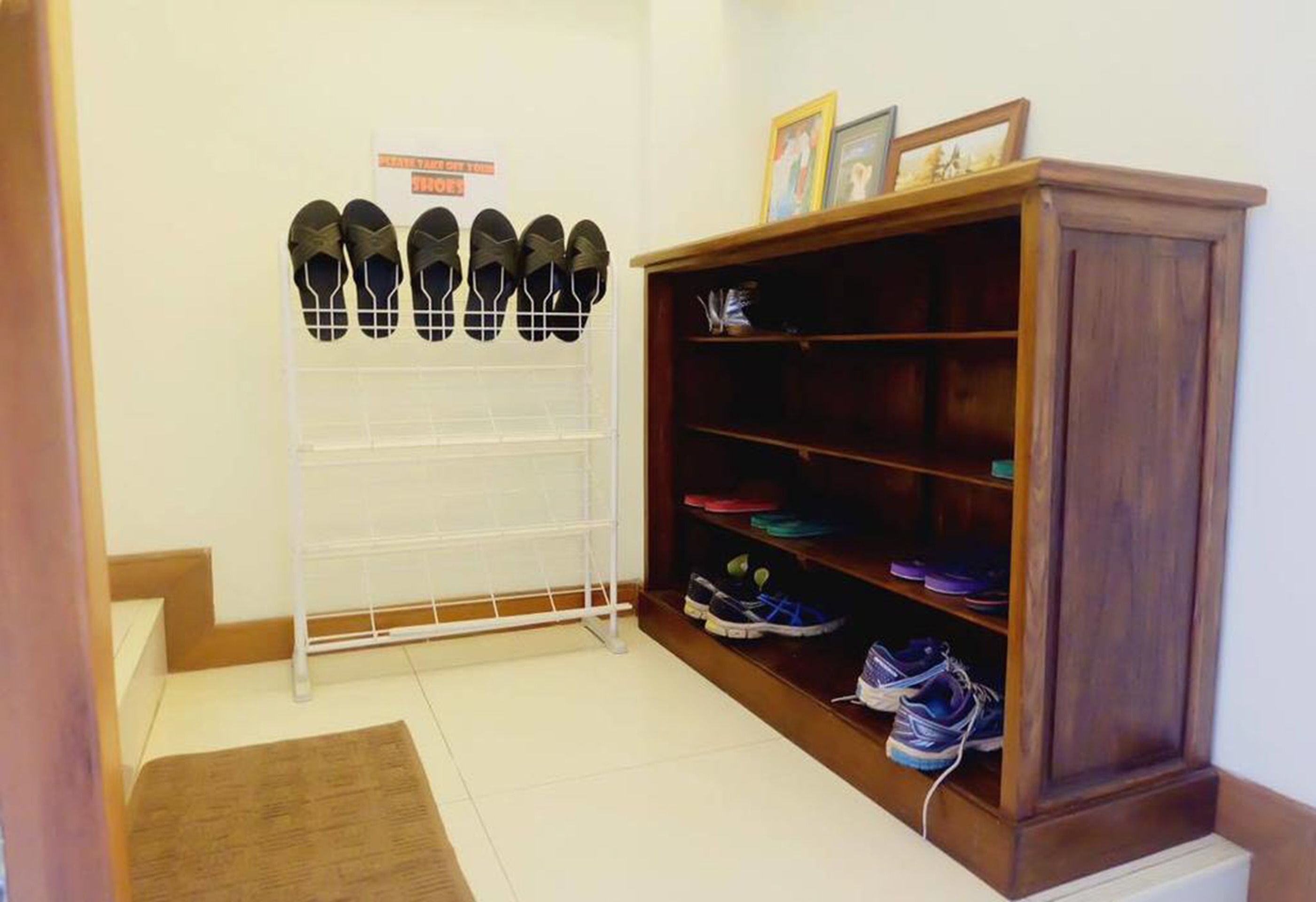 A shoe rack with multiple pairs of shoes and a wooden cabinet with shelves.