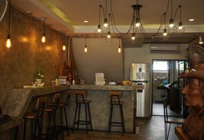 A bar area with a counter, stools, and hanging light fixtures. - T2B Home - Adults Only - Hostel (Chiang Mai)