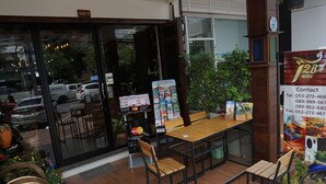 A restaurant with a wooden table and chairs, a menu board, and a contact sign. - T2B Home - Adults Only - Hostel (Chiang Mai)