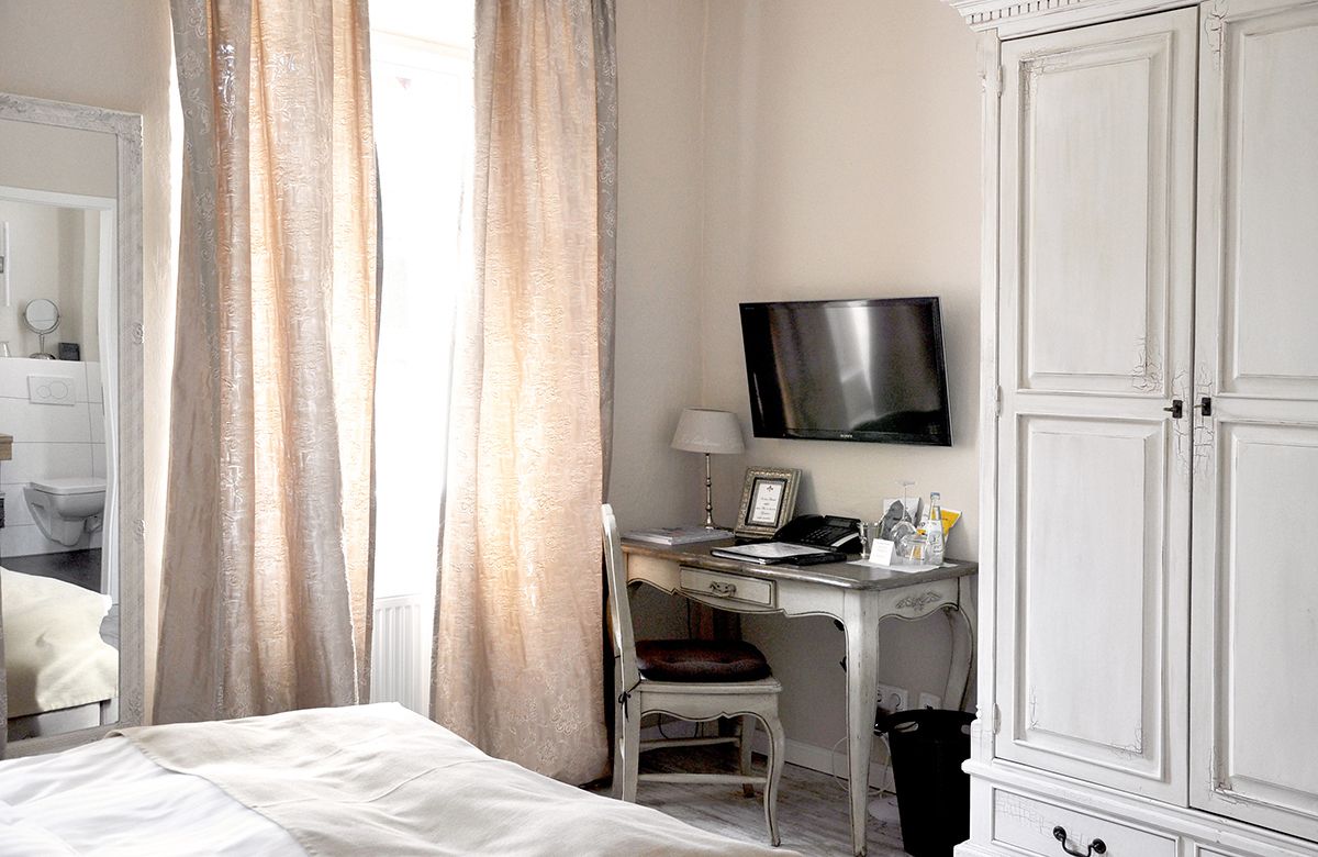 Habitació d'hotel amb llit, escriptori amb cadira, televisió i armari.