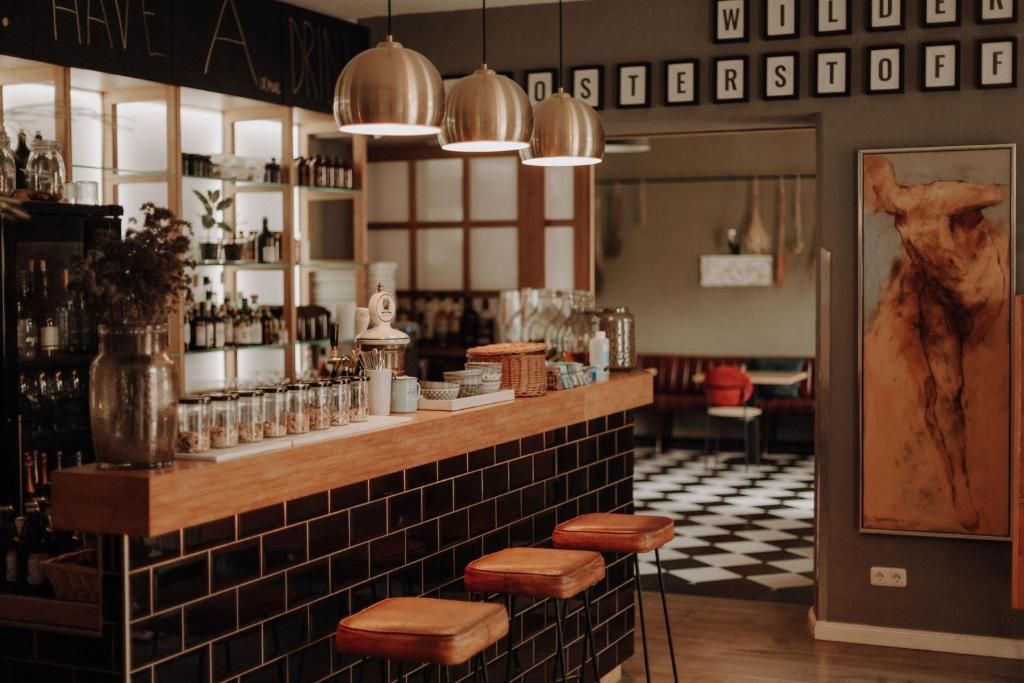 A bar area with a wooden counter, hanging pendant lights, and stools.