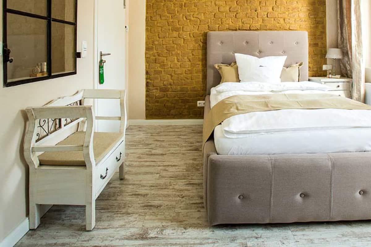 Ein Schlafzimmer mit einem großen Bett, einem Nachttisch, einer Kommode und einer Ziegelwand.