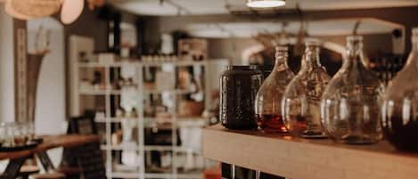A bar area with hanging lights, shelves with bottles, and a counter with glasses.