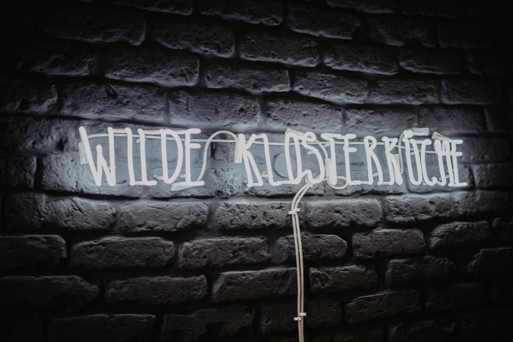 A neon sign with the text 'WILDE KOSTERBRUECKE' on a brick wall.