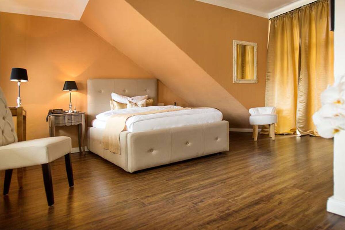 Ein Schlafzimmer mit einem Bett, einem Sessel, einem Nachttisch, einer Lampe und einem Spiegel.