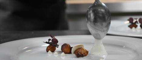 A chef's hand pouring a sauce onto a plate of food.