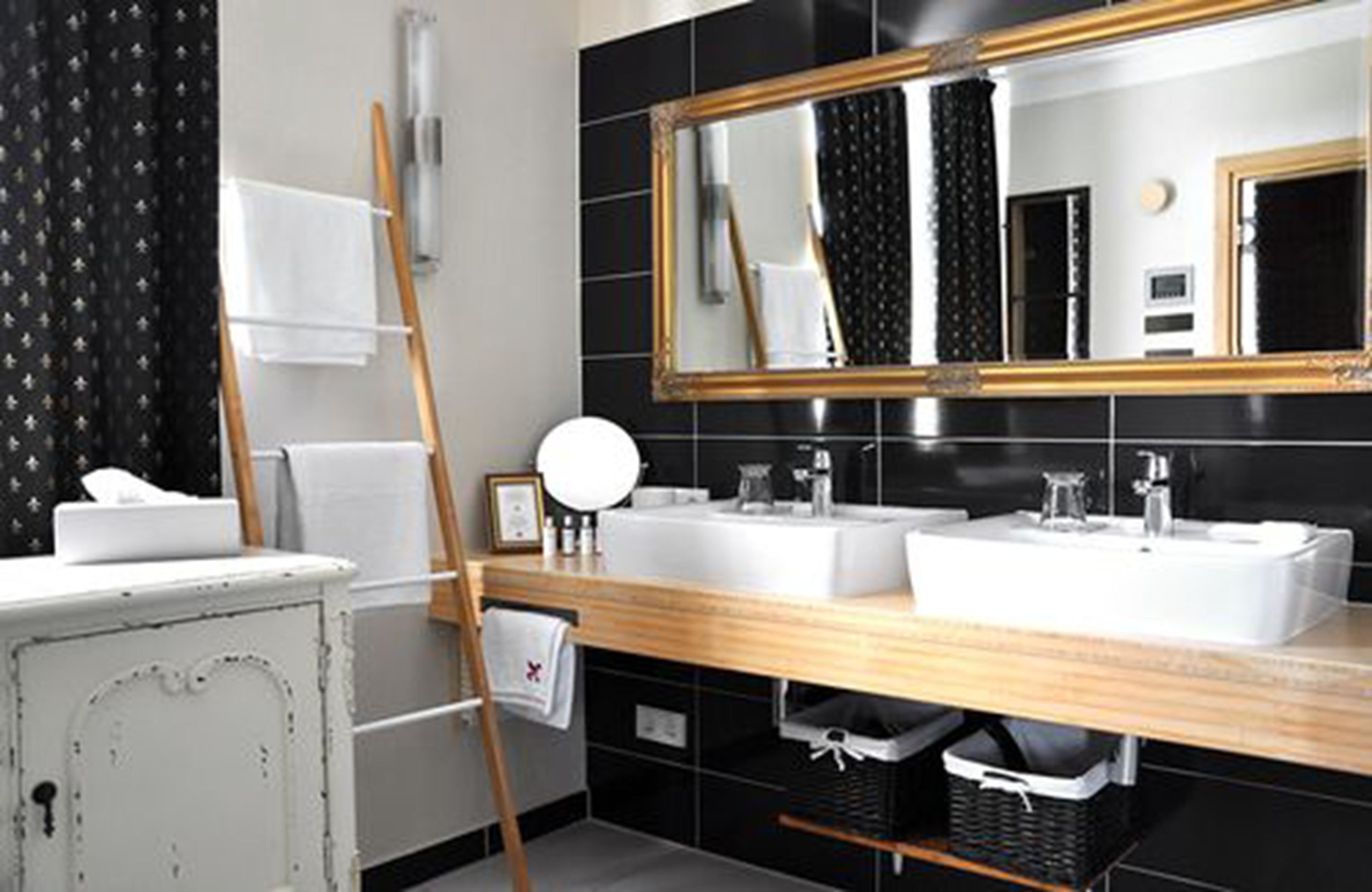 A modern bathroom with two sinks, a large mirror, and a wooden vanity.