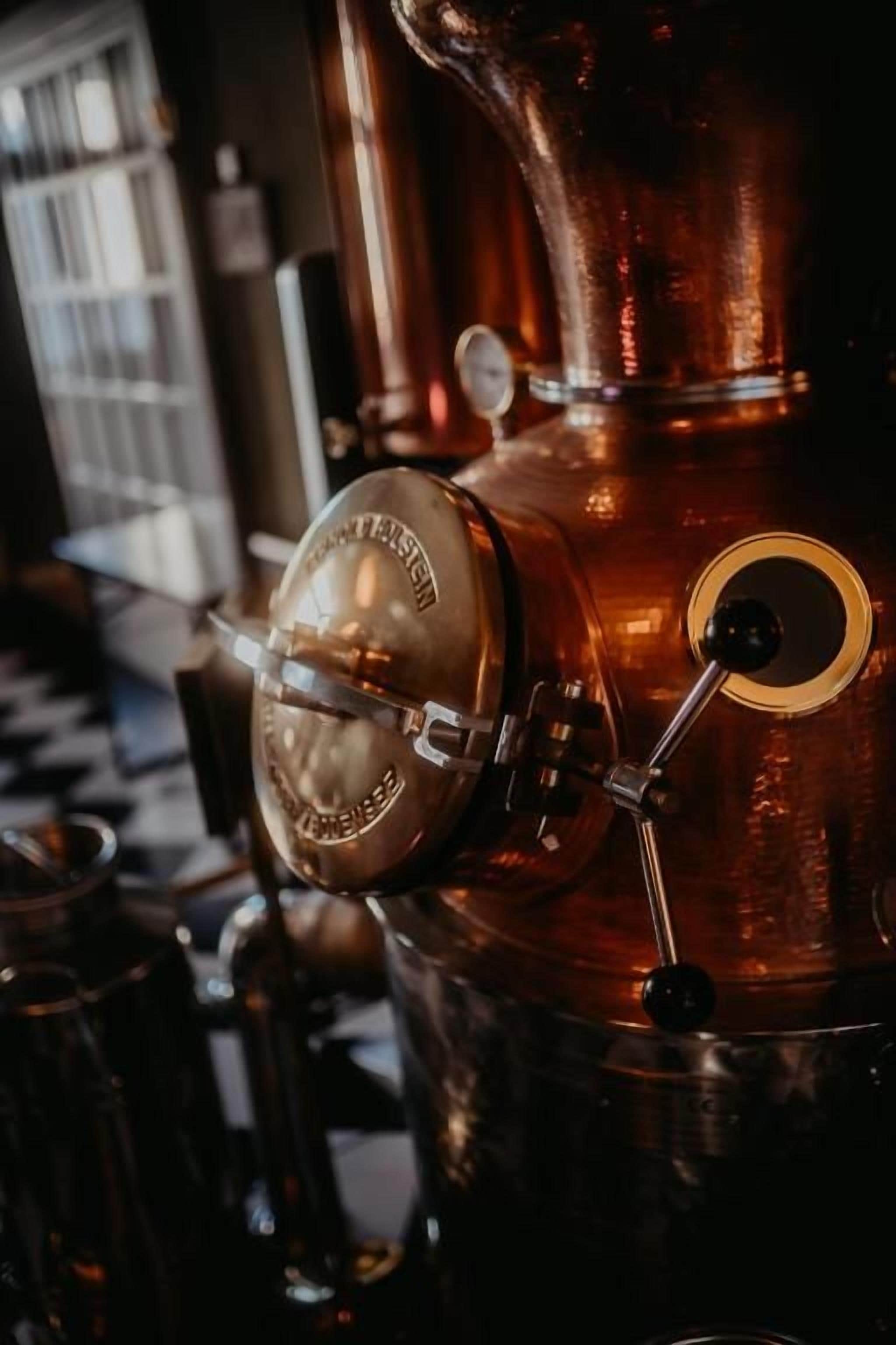 A copper distillation apparatus with a pressure gauge and a valve.