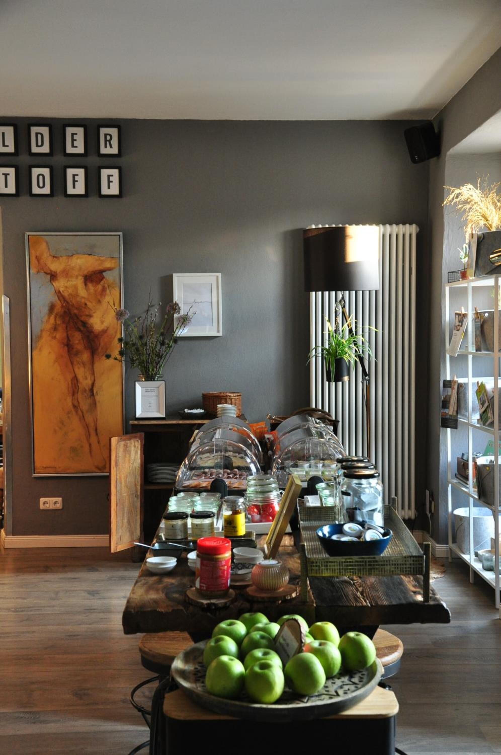 Una habitació amb una taula de buffet que mostra diversos plats, un quadre abstracte gran i una prestatgeria.